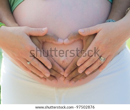belly of pregnant woman, with hands holding belly