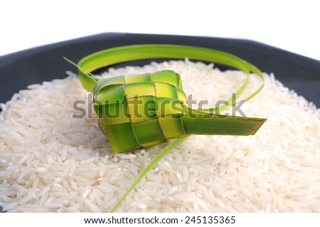 Ketupats, a natural rice casing made from young coconut leaves for cooking rice on rice grain and black glass plate