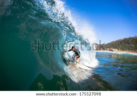Surfer Surfing Inside Blue  Surfer tube rides inside hollow crashing wave over shallow reef.Swimming water perspective of sport.