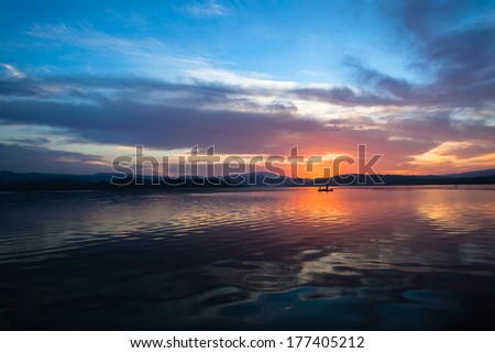 Dawn Colors Dam Waters Fishing  Dawn nature\'s color reflections over dam smooth waters sky clouds landscape with distant fishing boat