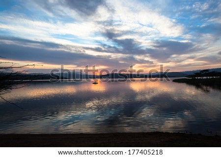 Dawn Colors Dam Waters Fishing  Dawn nature\'s color reflections over dam smooth waters sky clouds landscape with distant fishing boat