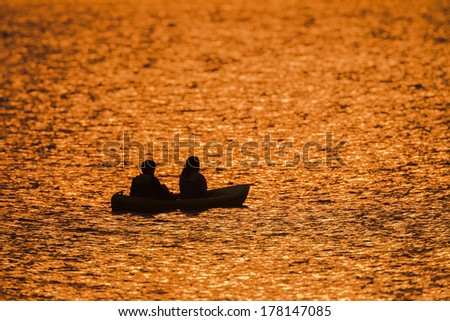 Dawn Colors Dam Waters Teenagers Fishing  Dawn nature\'s color reflections over dam smooth waters sky clouds landscape with two silhouetted teenagers girl boy fishing