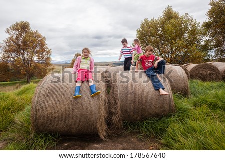 Children Farm Hay Bales Playtime Young children play and talk standing on mountain farm grass hay bales for cattle .