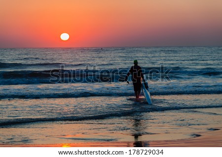 Dawn Surf-Ski Paddler Beach Ocean  Surf-ski paddler silhouetted beach entry into ocean waters for training at dawn sun rising in horizon sky