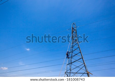 Electrical Tower Cable Maintenance  Electricians climb steel metal pylon tower for cable maintenance against blue sky