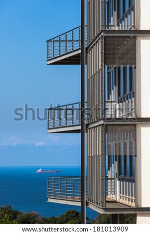 Ocean Balcony Porch Building Ship Building section of three open balcony porch overlooking blue ocean with distant ship