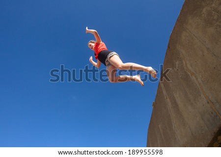 Girl Jumping Blue Sky Parkour Teen girl jumping off wall against blue sky onto beach in parkour