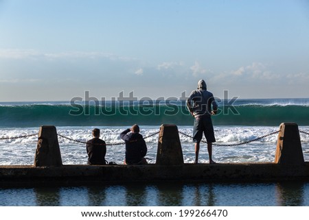 Ocean Wave Power Spectators Pool Wall Wave crashing water power energy and  scenic nature with unidentified spectators watching on tidal pool wall.