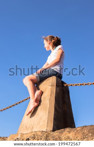 Teen Girl Sitting Blue Sky Teenager girl relaxing sitting concrete tidal pool block looking out at ocean waves in morning blue sky.