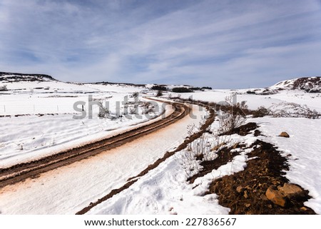 Dirt Road Tracks Snow Mountains Dirt road tracks over  high plateau mountain terrain in winter snow scenic landscape