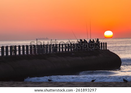 Fishing Sunrise Ocean\
Fishermen fishing dawn on pier jetty as sun rises on the ocean horizon.