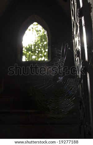spider-web on door of tomb vault, light shining through grilled window