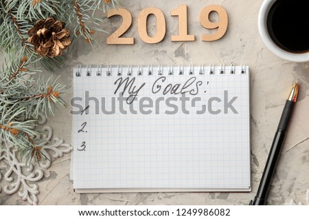 goal 2019. text in notebook with new year decor and christmas tree branches on a light background.