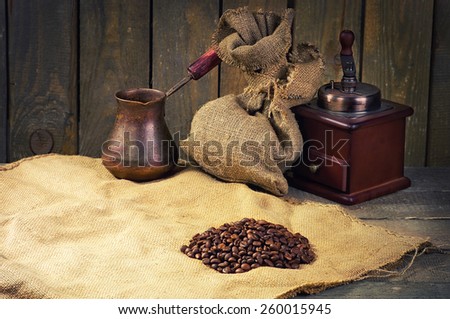 coffee beans, manual coffee grinder and coffee maker on sacking in vintage grunge style. composition shifted labeling