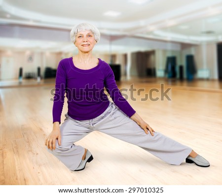 charming beautiful elderly woman doing exercises while working out playing sports in fitness training room