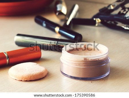 Compact pocket powder and a powder puff and other cosmetics on the table