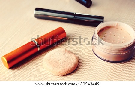 Powder, powder puff, mascara, eyeliner and other cosmetics on the table