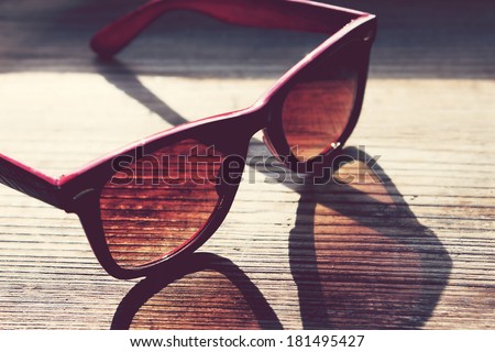Black and red vintage sunglasses on a wooden table closeup
