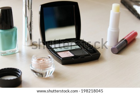 Set of eyeshadow, mascara, primer, turquoise blue nail polish and other cosmetics on a dressing table