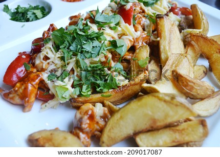 Big white plate with fried potatoes, meat and cheese and sauce