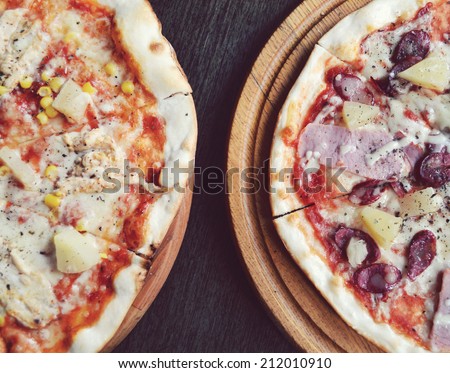 Two delicious pizzas with pineapple and meat