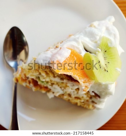Slice of fruit cake with cream, kiwi and orange