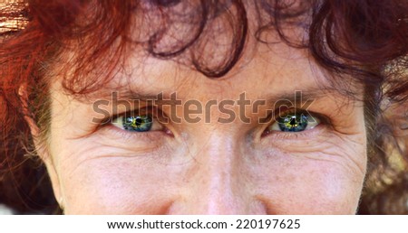 Bright blue eyes of a happy beautiful woman with red hair in her fourties