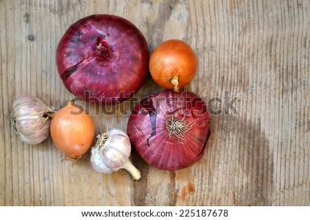 Red and bulb onions with whole organic garlic on wooden table
