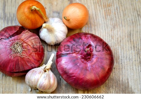 Red and bulb onions with whole organic garlic on wooden table