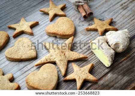 Gingerbread cookies in shapes of heart, star and man with ginger root on wooden table