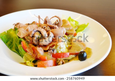Big plate with seafood salad with olives and squid