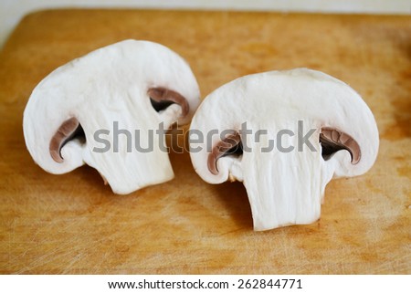 Raw white mushrooms champignons on wooden board