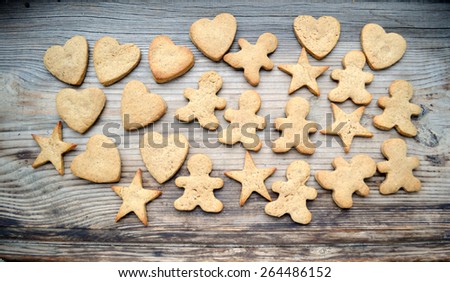 Gingerbread cookies in shapes of heart, star and man with cinnamon stick and ginger root on wooden table