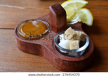 A set of tea toppings and sweeteners: a bit of honey, brown and white sugar, and a lemon