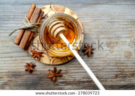 Golden honey with honeystick. cinnamon and anise stars on wooden table