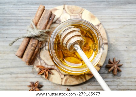Golden honey with honeystick. cinnamon and anise stars on wooden table