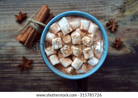 Black and blue cup of hot cocoa with marshmallows, star anise and cinnamon