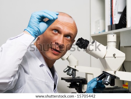 Researcher in front of microscope looking on microscope slide