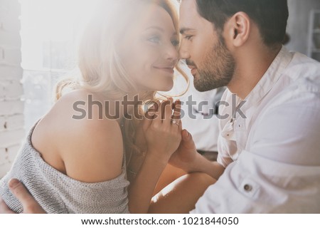Real love. Beautiful young couple bonding and smiling while sitting in the bedroom