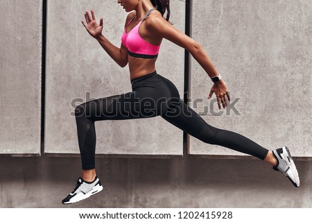 Long jump. Modern young woman in sports clothing jumping while exercising outdoors
