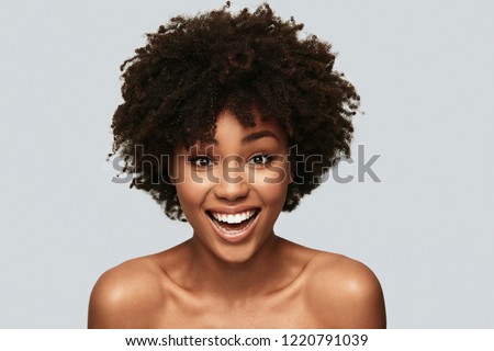 Impossible to resist her. Attractive young African woman looking at camera and smiling while standing against grey background