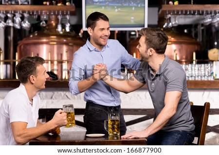 Old friends meeting. Three cheerful friends meet each other in beer pub