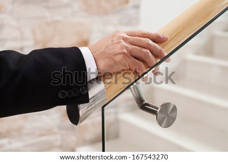 Moving up. Close-up of man in formal wear holding hand on wooden rail