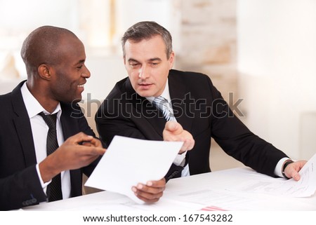 Contract On Good Conditions. Two Cheerful Business People In Formalwear Discussing Something And Pointing A Paper