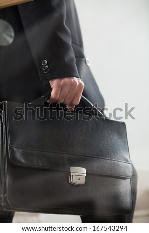 Moving up. Cropped side view image of man in formal wear carrying a briefcase and moving up by stairs