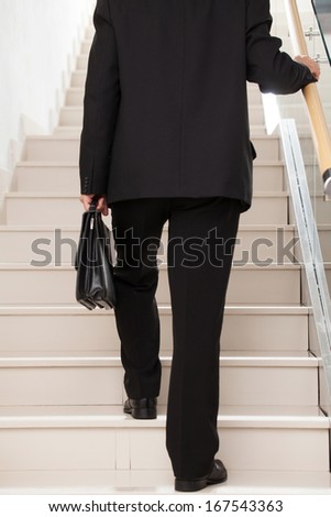 Moving up. Cropped rear view image of man in formal wear moving up by stairs
