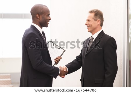 Business Meeting. Two Cheerful Business Men Shaking Hands And Looking At Each Other