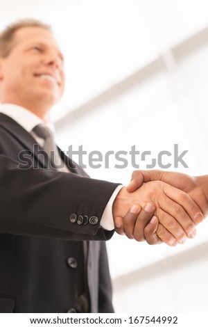 Sealing a deal. Close-up of low angle view of business men shaking hands
