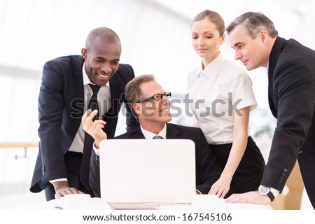 Discussing a new project. Two business people in formalwear discussing something while man pointing a paper with a pen and smiling