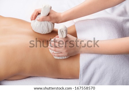 Healing back massage. Top view of attractive young woman with flower in head lying on front while massage therapist massaging her back